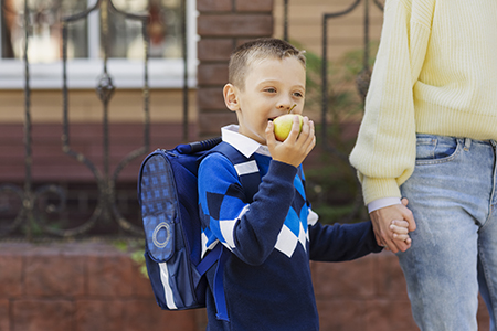 Young boy with a backpack holding his parent’s hand on his first day of preschool in Kerrville, Texas.  Help your child feel confident on first day of school with this tips