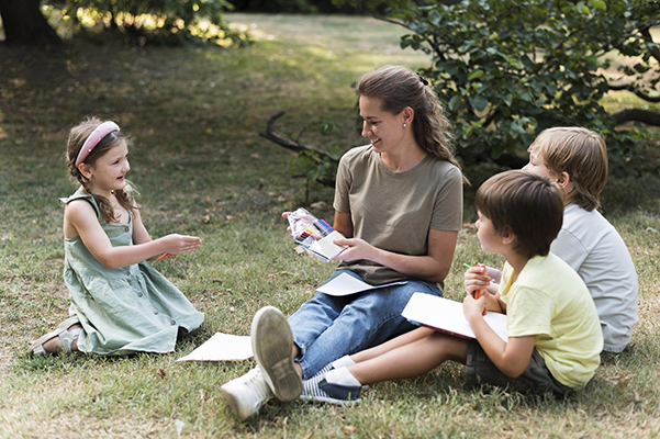 A teacher engages young learners in a calm outdoor lesson that supports safety, routine, and confidence.