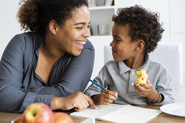 Child eating snack with teacher support in preschool classroom